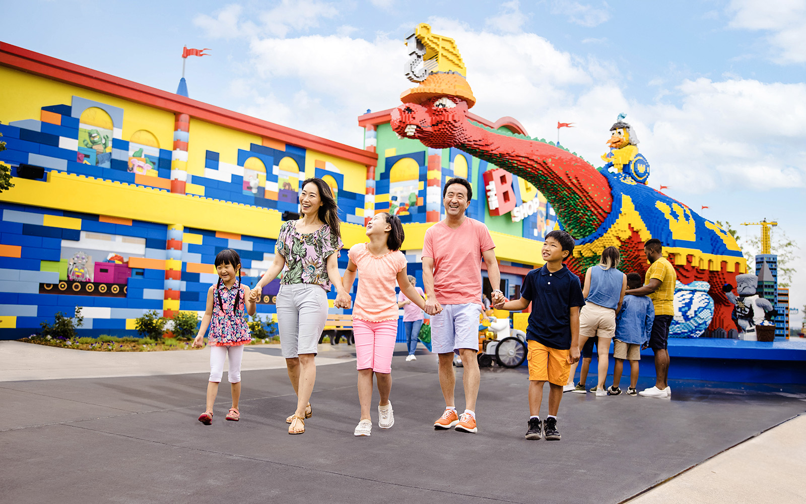 Guests enjoying a colorful day at Legoland New York with Lego sculptures in the background.