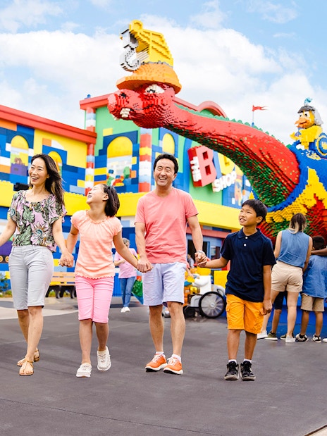 Guests enjoying a colorful day at Legoland New York with Lego sculptures in the background.