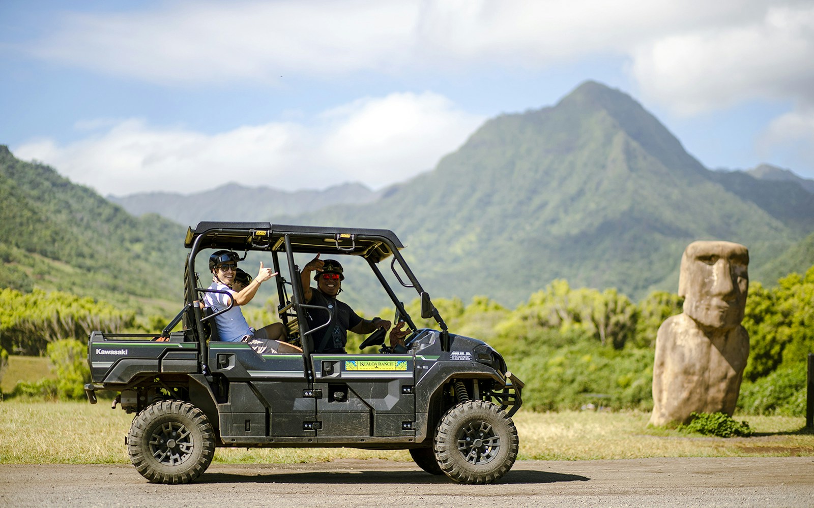 UTV Raptor tour at Kualoa Ranch, Hawaii with mountain and statue in background.