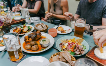 Guests enjoying Czech food and beer at a table with roast meat, salad, and bread.