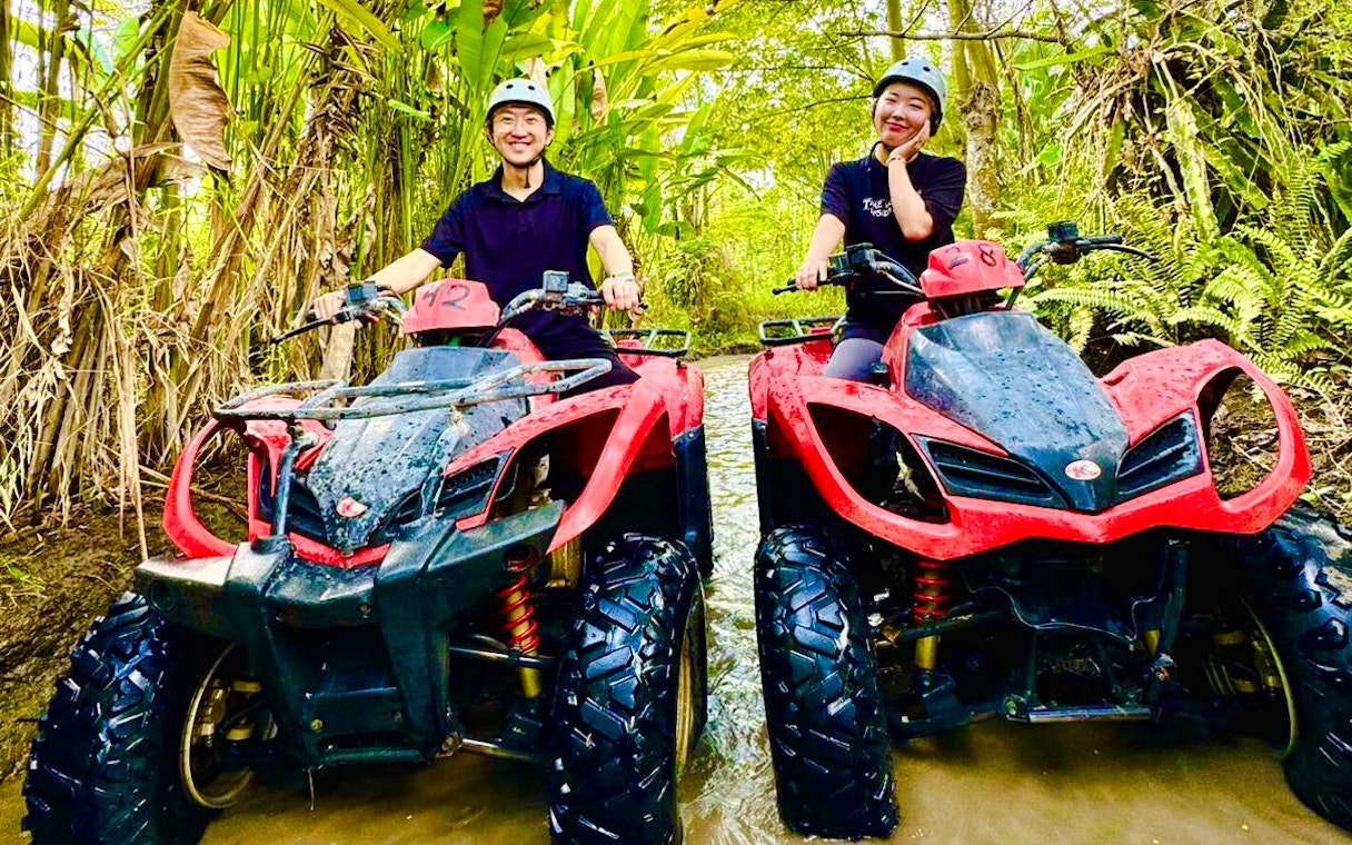 Couple riding ATVs through a forest trail during Mount Batur tour.