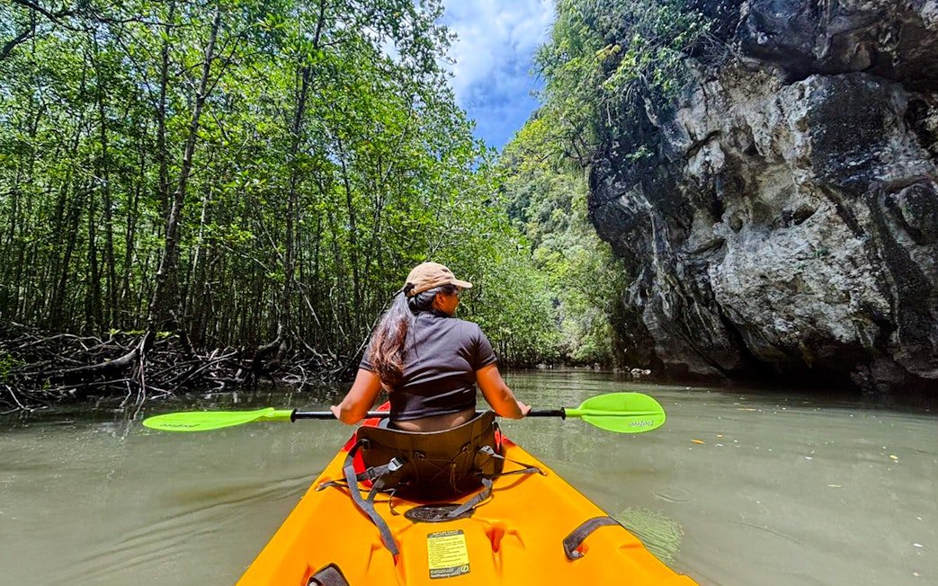 Tourist kayaking through Ao Thalane mangrove forest in Thailand.