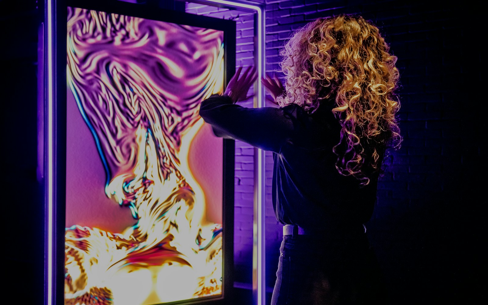 Person interacting with vibrant digital art at AMAZE Amsterdam Immersive Experience.