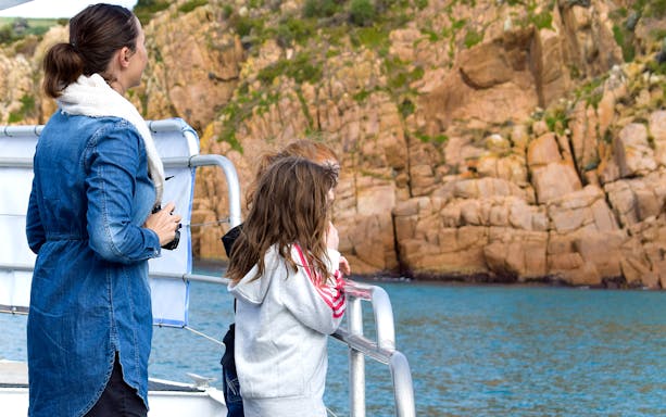 Visitors on a boat viewing Cape Woolamai's rocky coastline during a Phillip Island morning cruise.