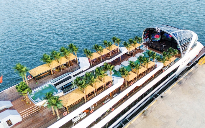 Aerial view of a cruise ship deck with palm trees and cabanas for a dolphin cruise.