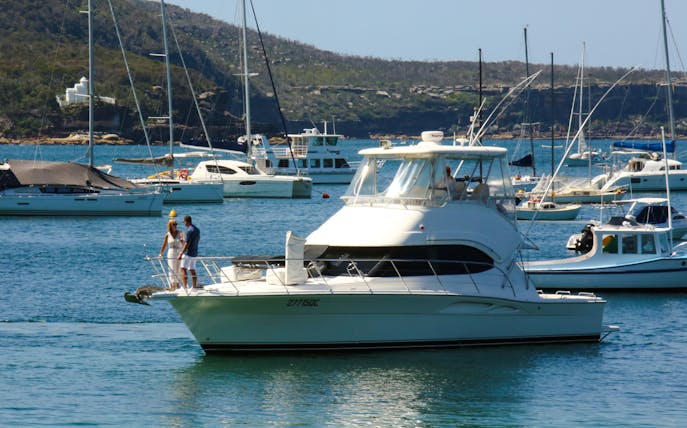 Sydney Harbour cruise boat with passengers enjoying the view, surrounded by yachts.