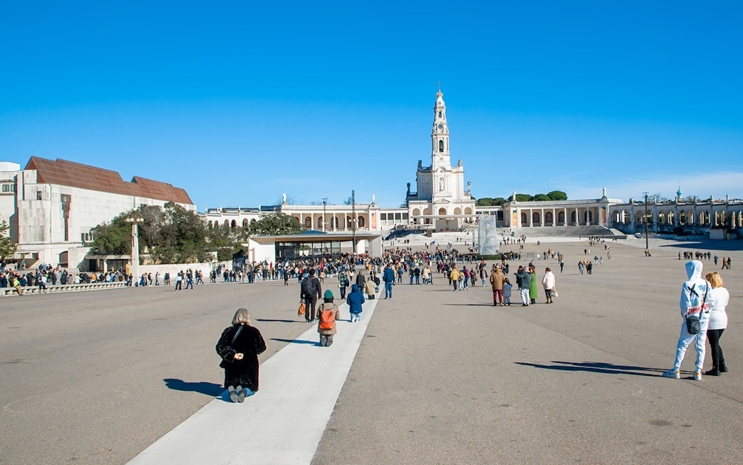 Visitors at the Square of the Basilica of Our Lady of Fatima, Portugal, seeking blessings.