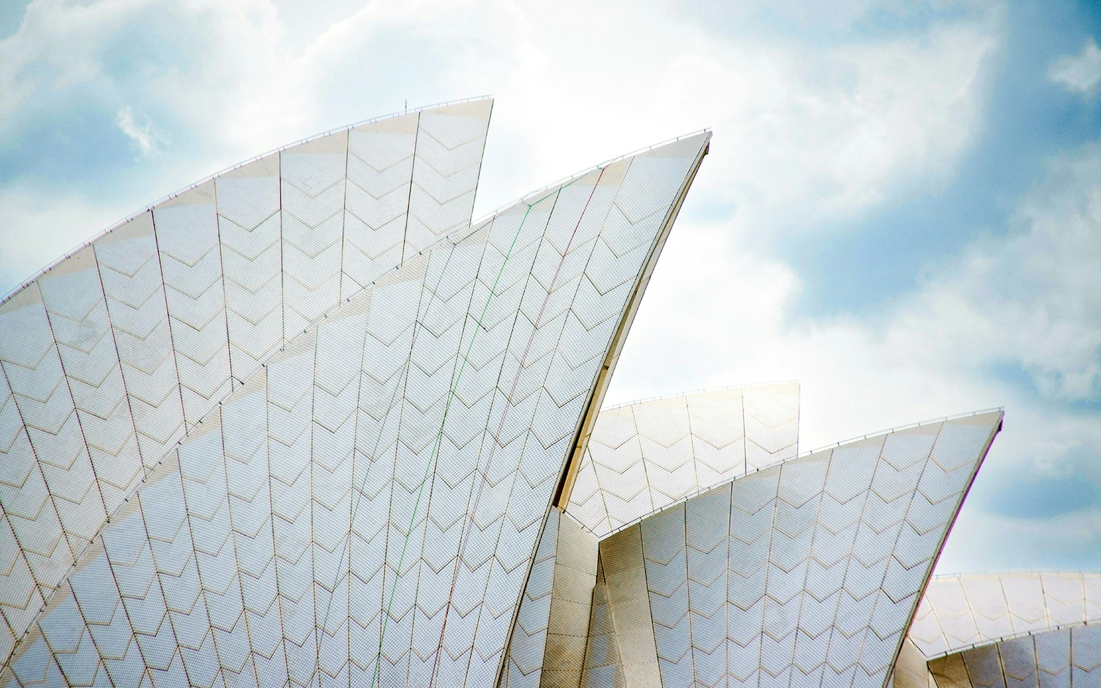 Sydney Opera House roof sails against a cloudy sky.