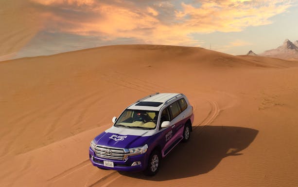 SUV driving through Mleiha desert dunes near Fossil Rock.