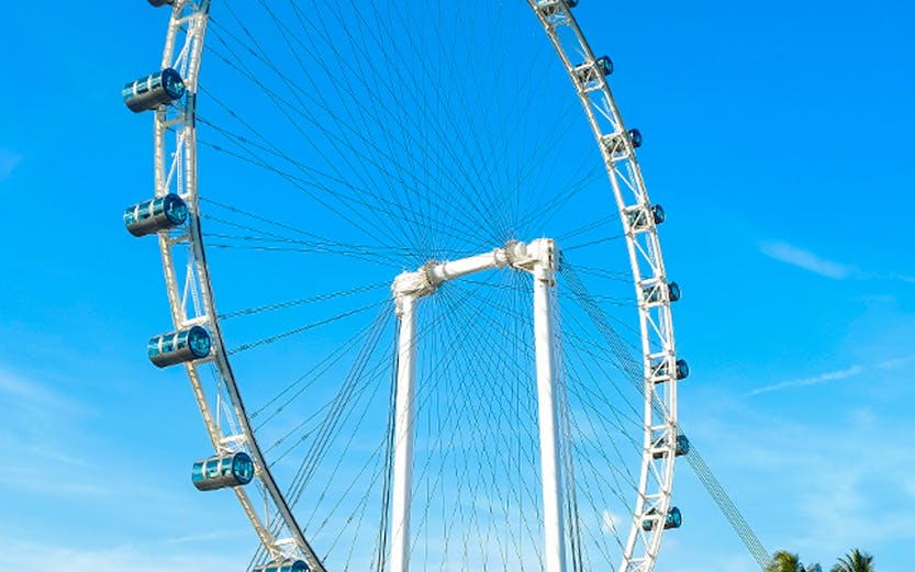 Ferris wheel at Singapore Flyer against blue sky.