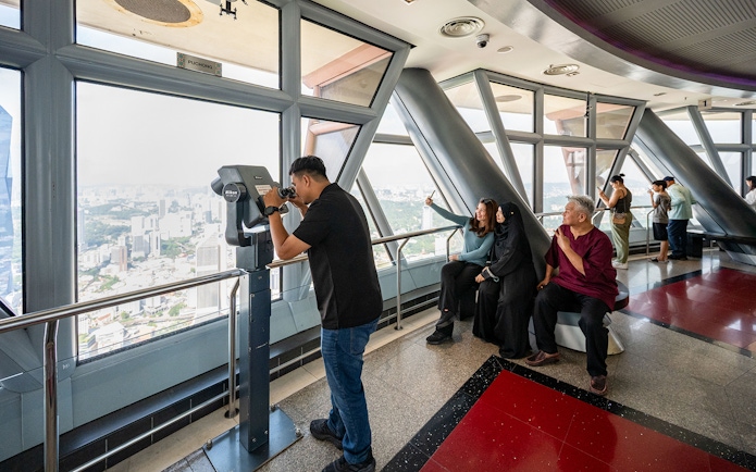 Tourists enjoying city views from Kuala Lumpur Tower Observation Deck.