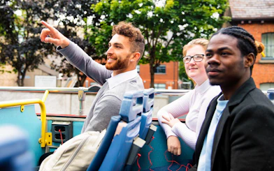 Tourists enjoying a ride on a double-decker bus in Dublin, part of City Sightseeing tour.