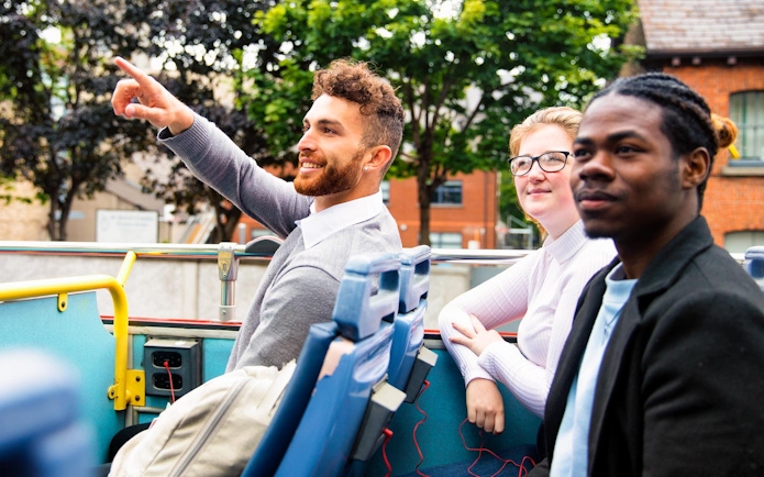 Tourists enjoying a ride on a double-decker bus in Dublin, part of City Sightseeing tour.