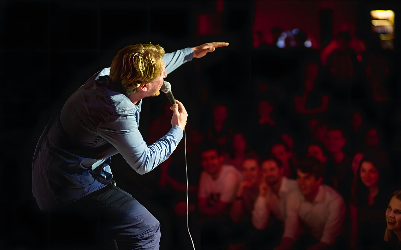 Comedian performing on stage at The Comedy Embassy with audience laughing.