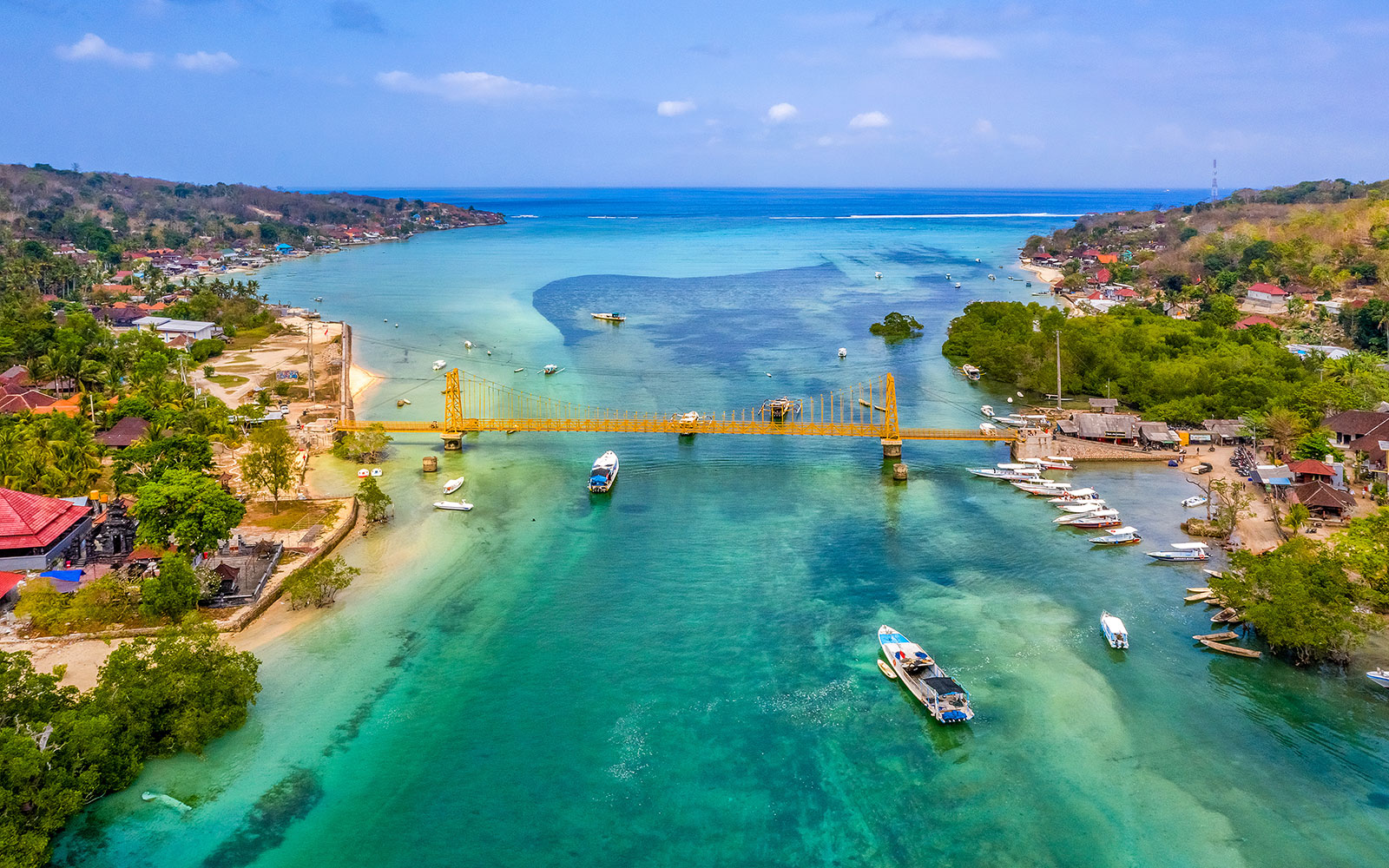 Yellow Bridge connecting Nusa Ceningan and Nusa Lembongan over turquoise waters with boats nearby.