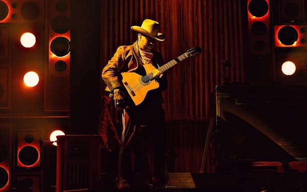Performer with guitar on stage during Mexodus the Musical, Broadway.