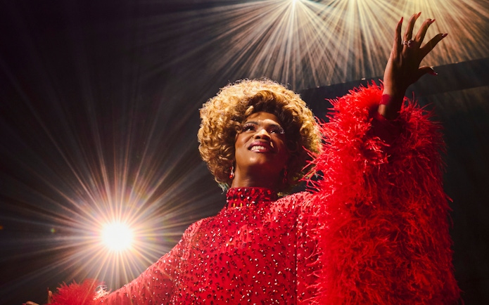 Performer in red costume on stage during Kinky Boots production.