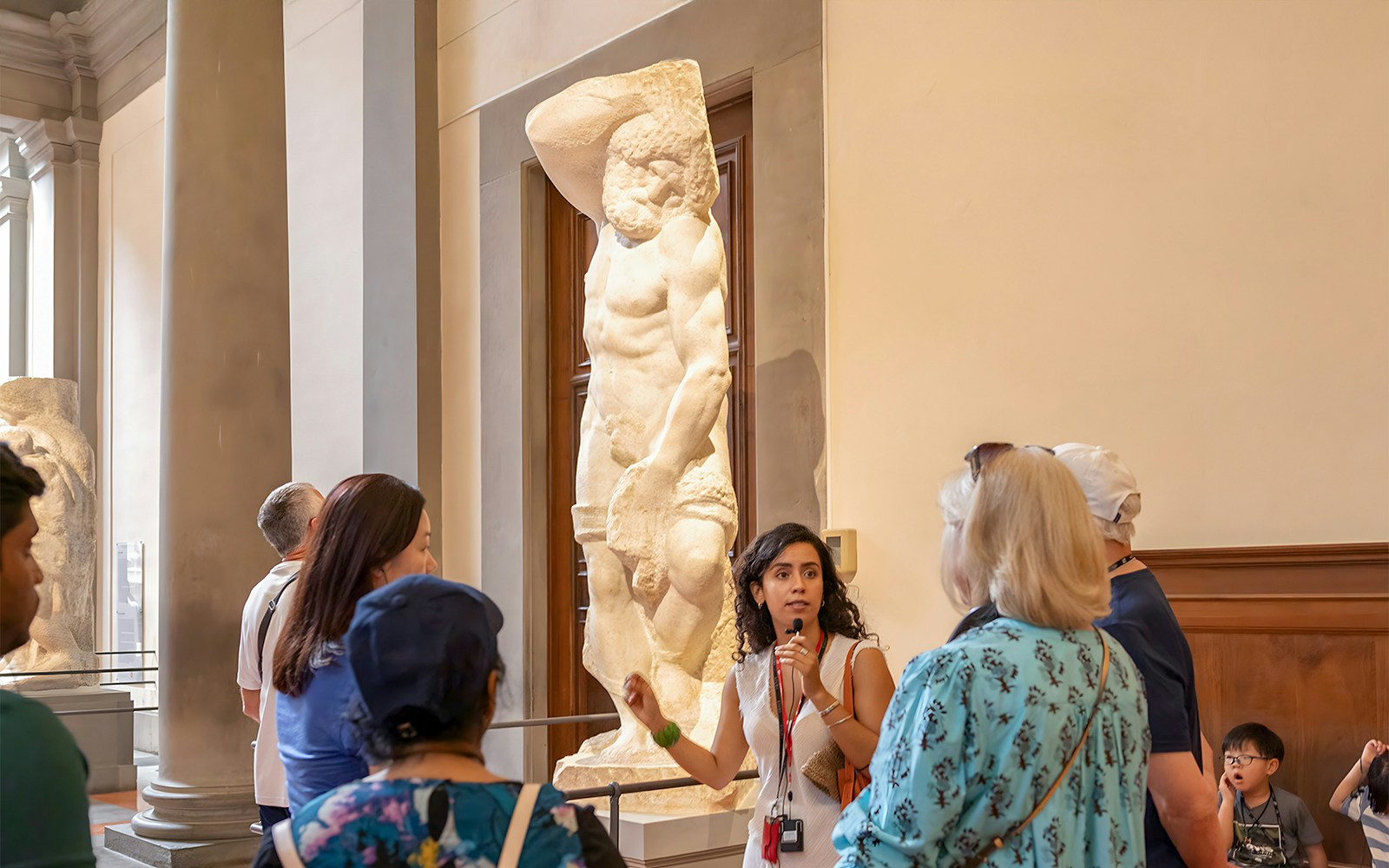 Guide explaining Michelangelo's unfinished sculpture in Hall of Prisoners, Accademia Gallery, Florence.