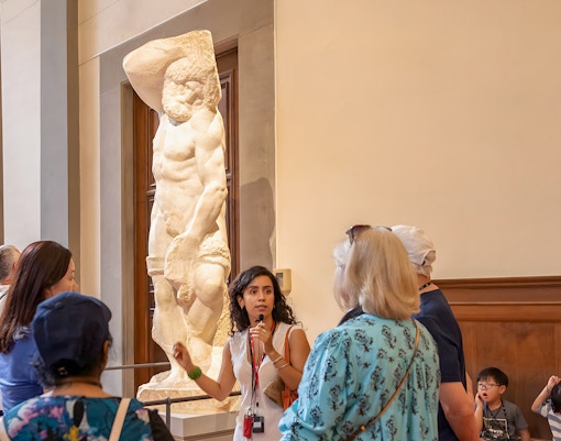 Guide explaining Michelangelo's unfinished sculptures to group in Hall of Prisoners, Accademia Gallery, Florence.
