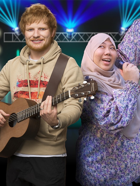 Wax figure of a musician with a guitar and a visitor singing at Madame Tussauds Singapore.