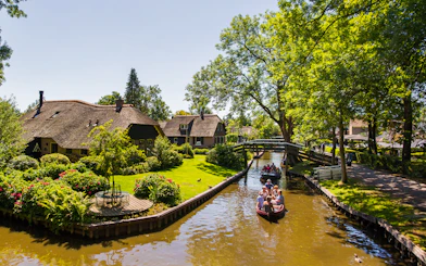 Canal boat tour in Giethoorn with thatched cottages and lush greenery.