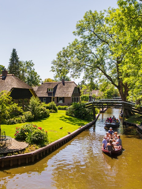 Canal boat tour in Giethoorn with thatched cottages and lush greenery.