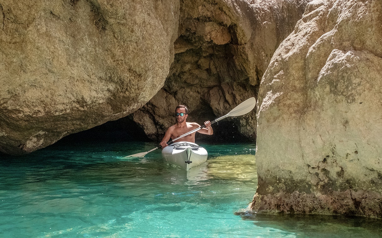 Kayaker navigating through rocky cave waters in Capri.