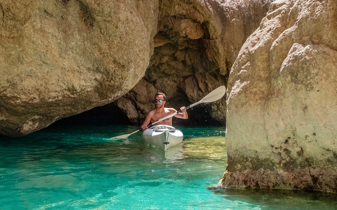Kayaker navigating through rocky cave waters in Capri.