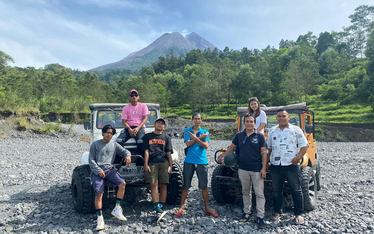 Group posing with jeeps on rocky terrain during Sunrise Long Trip Lava Tour by JWM Adventure, Dubai.