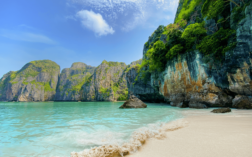 Beach with turquoise water and limestone cliffs at Maya Bay, Thailand.