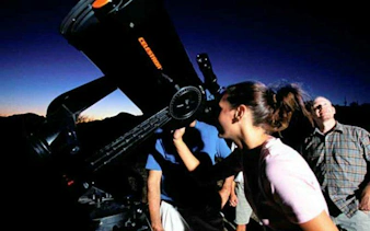 People stargazing through a telescope at Teide National Park, Tenerife during sunset tour.