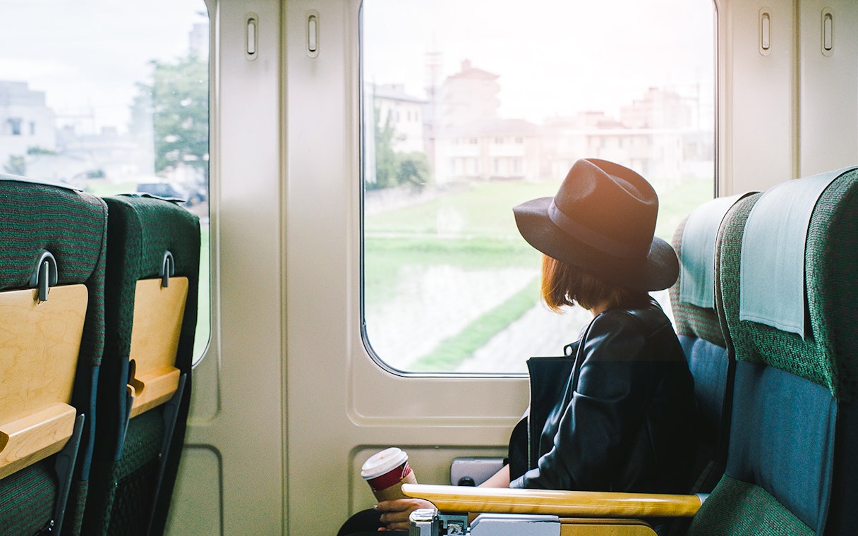 Woman on a train in Japan looking out the window at cityscape.
