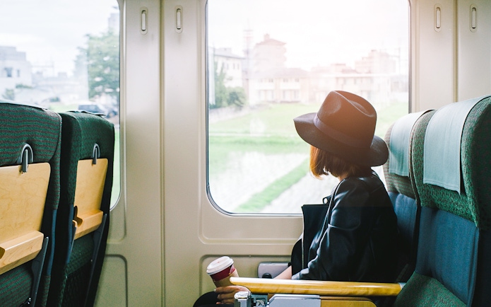Woman on a train in Japan looking out the window at cityscape.
