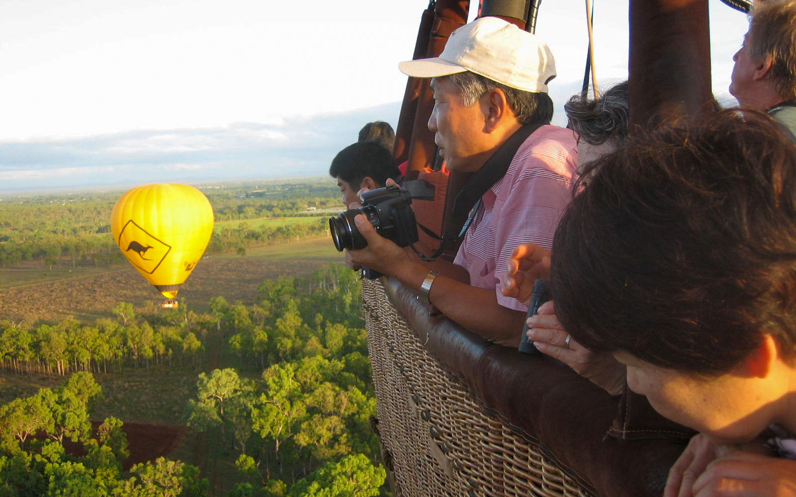 Hot air balloon over Cairns landscape with passengers enjoying the view.