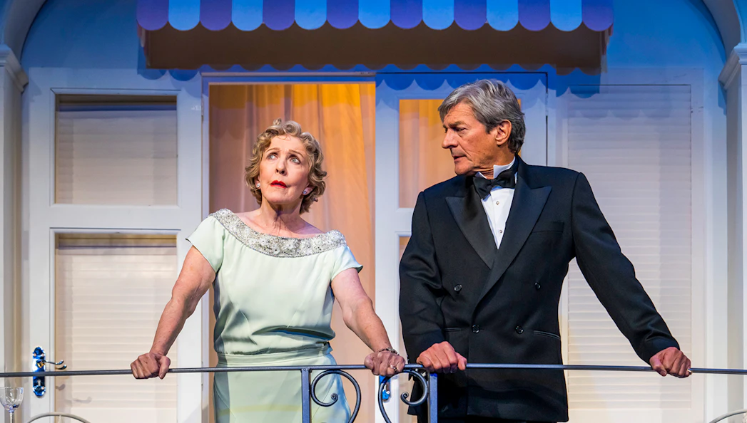Two actors in formal attire on a balcony during a scene from "Private Lives.
