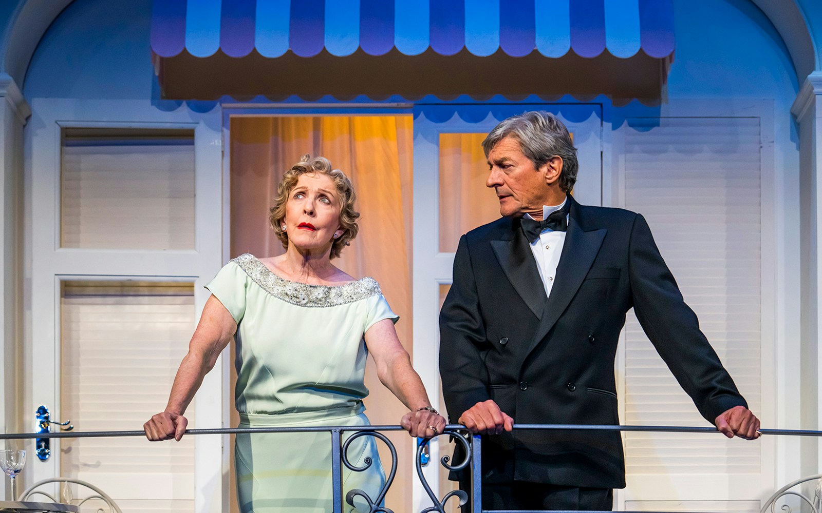 Two actors in formal attire on a balcony during a scene from "Private Lives.