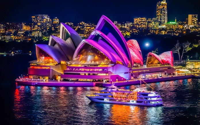 Sydney Opera House illuminated during Vivid Lights Cruise at night.