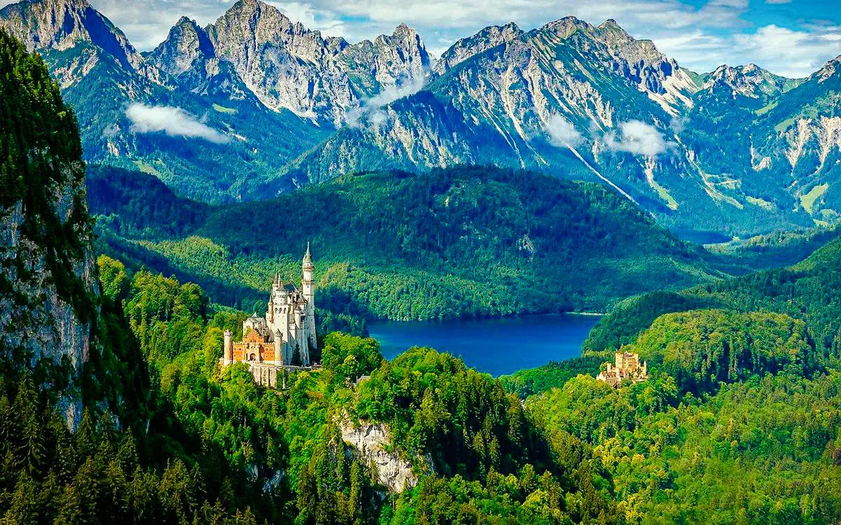 Neuschwanstein Castle surrounded by lush forests and mountains in Bavaria, Germany.