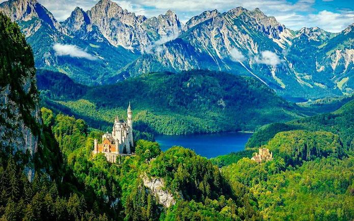 Neuschwanstein Castle surrounded by lush forests and mountains in Bavaria, Germany.