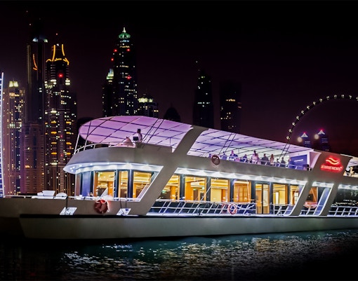 Dinner cruise boat with live music on Dubai Marina at night.