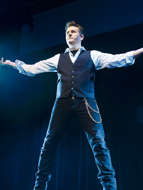Magician performing on stage during the Evolution Magic Show.