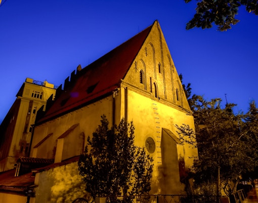 Old New Synagogue illuminated at night in Prague's Jewish Quarter.