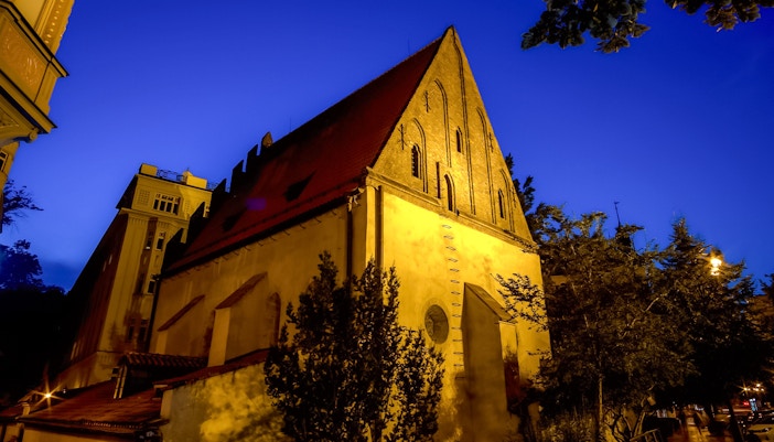Old New Synagogue illuminated at night in Prague's Jewish Quarter.