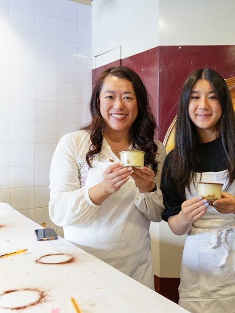 Participants holding tiramisu in a Rome cooking class kitchen.