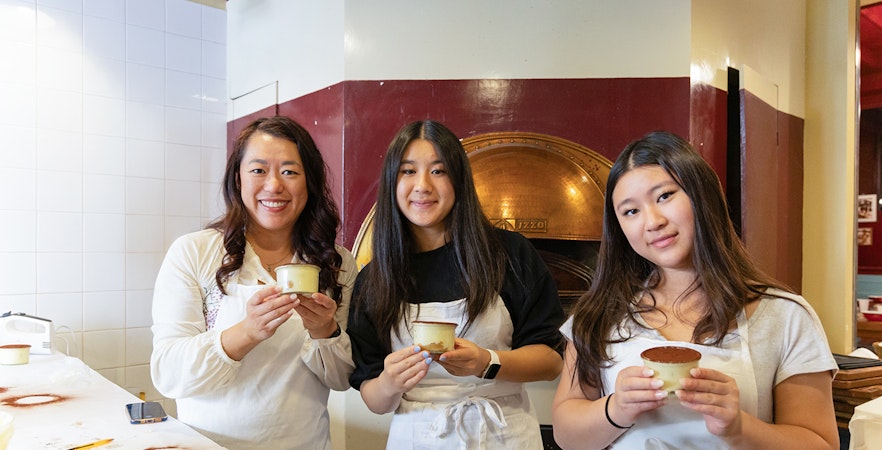 Participants with tiramisu in a Rome cooking class kitchen.