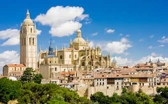 Segovia Cathedral with its Gothic architecture and bell tower under a blue sky.
