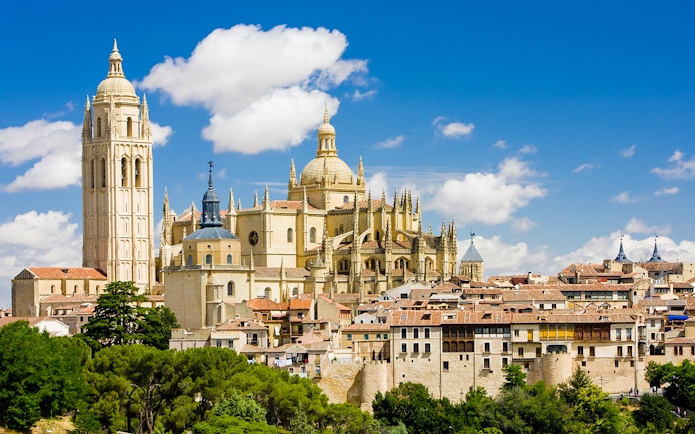 Segovia Cathedral with its Gothic architecture and bell tower under a blue sky.