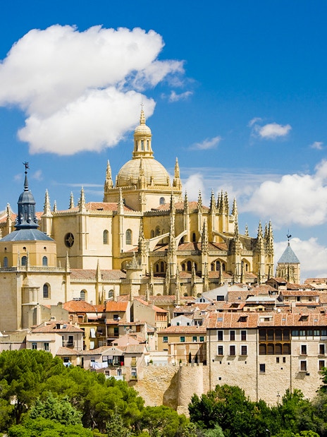Segovia Cathedral with its Gothic architecture and bell tower under a blue sky.