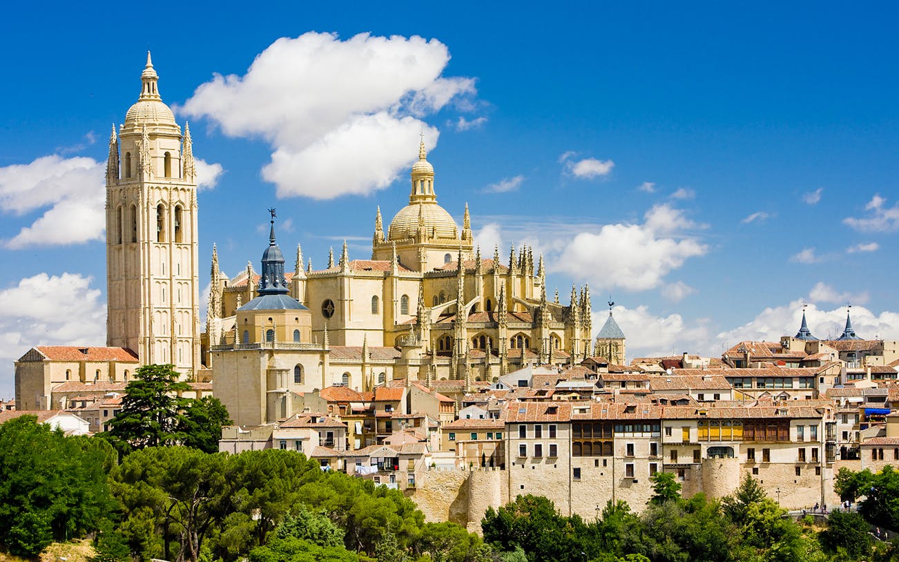 Segovia Cathedral with its Gothic architecture and bell tower under a blue sky.