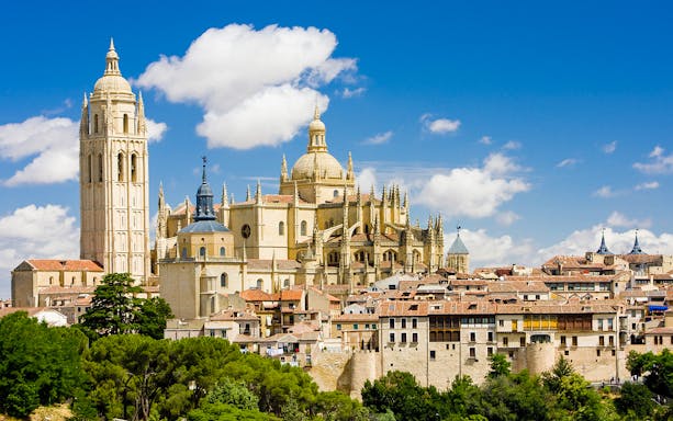 Segovia Cathedral with its Gothic architecture and bell tower under a blue sky.